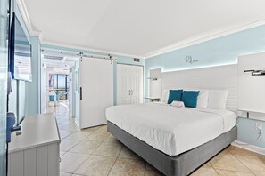 Une chambre à coucher comprenant un lit, un bureau, une armoire et une porte donnant sur un balcon.