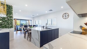 Een moderne keuken met een centraal eiland, barkrukken en een eethoek met uitzicht.
