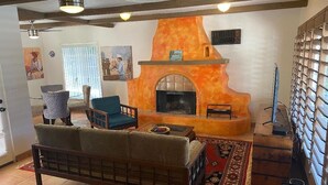 A living room with a fireplace, a sofa, a coffee table, and a patterned rug. - Classic Charming Hacienda (Palm Springs)