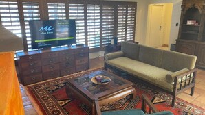 A living room with a sofa, a coffee table, and a television on a stand. - Classic Charming Hacienda (Palm Springs)