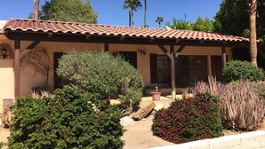 A building with a tiled roof, surrounded by various types of vegetation, including bushes and cacti. - Classic Charming Hacienda (Palm Springs)