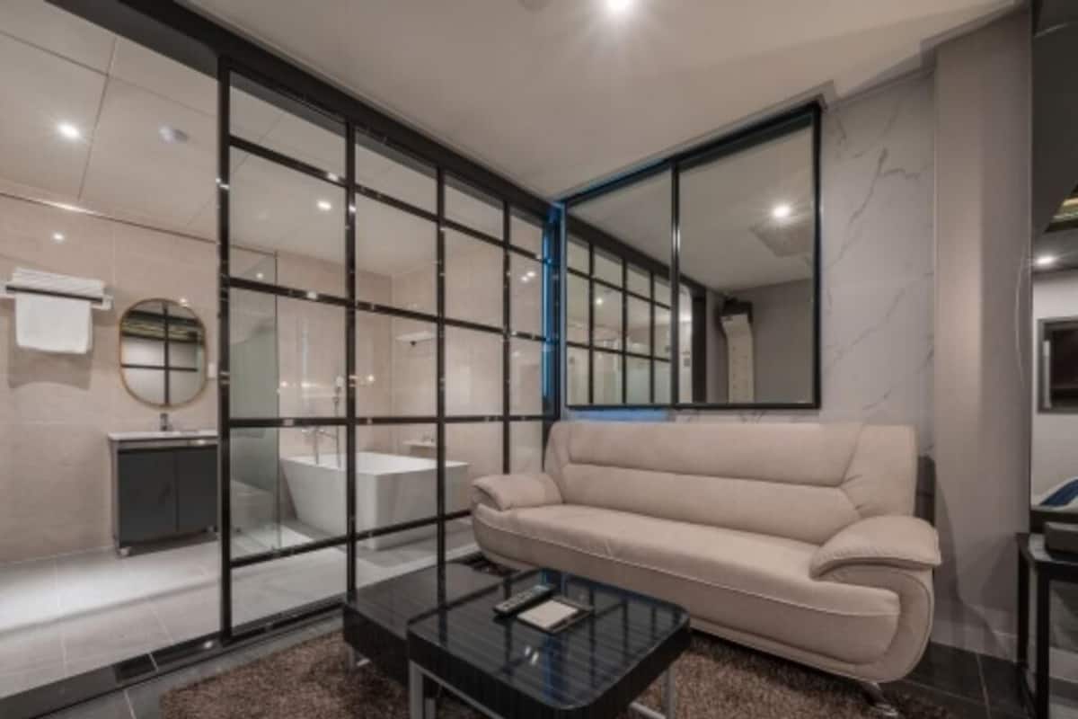 A modern bathroom with a glass partition, a beige sofa, and a glass coffee table.
