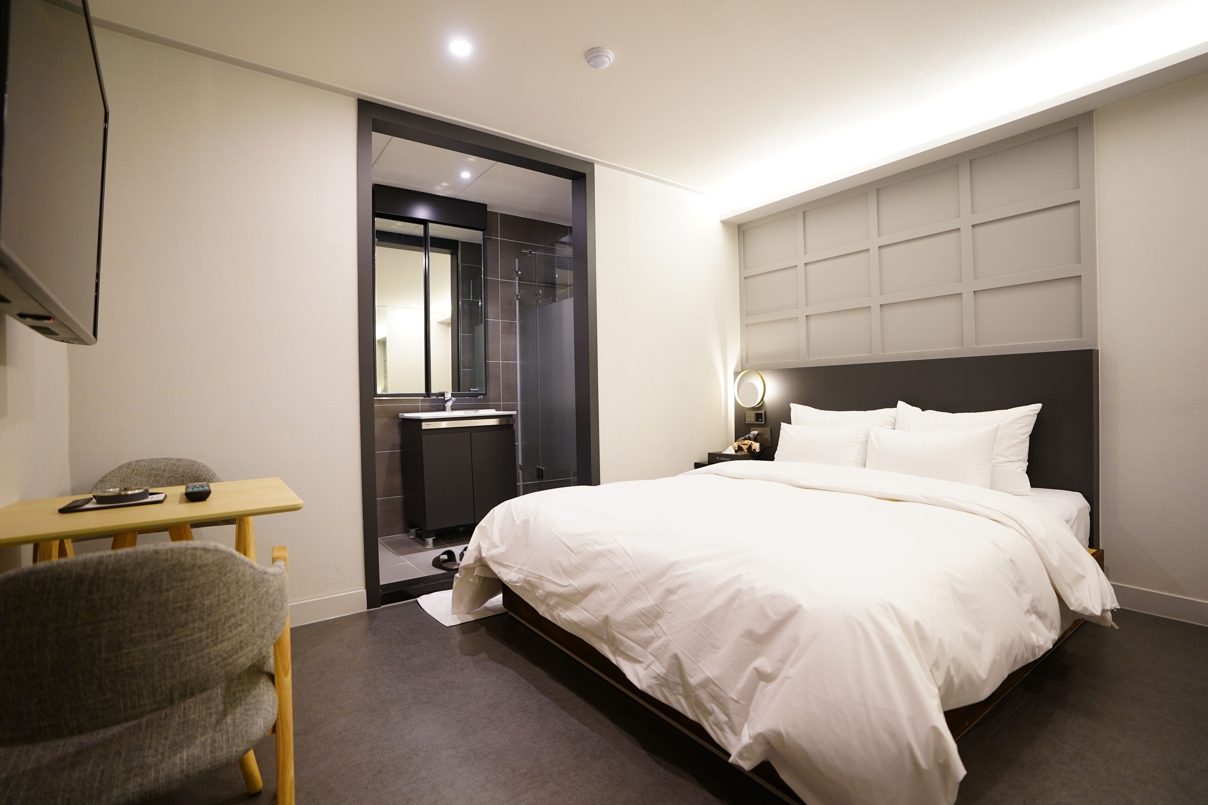A modern hotel room with a large bed, a desk, and a chair.