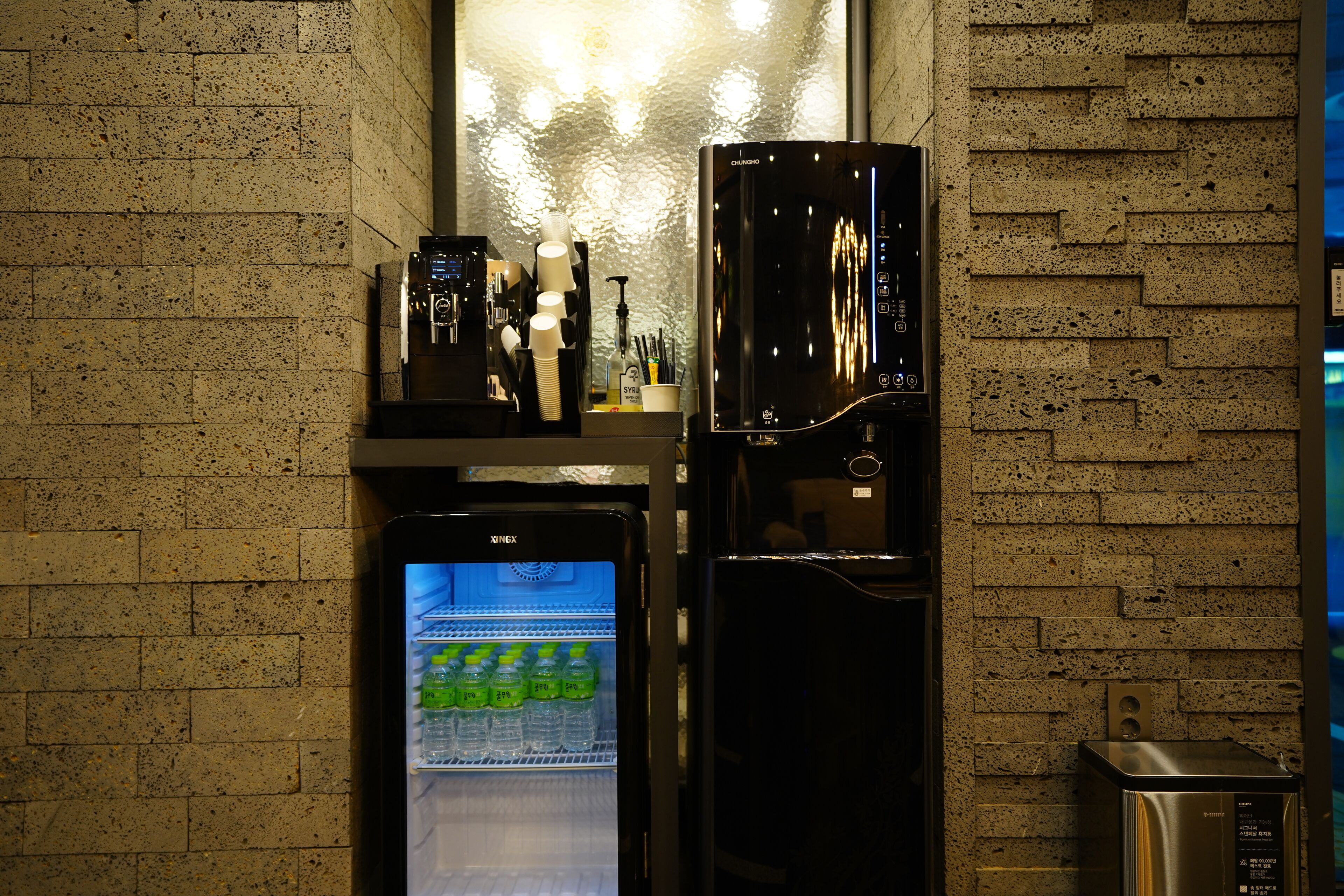 Una cocina con refrigerador, cafetera y dispensador de agua.