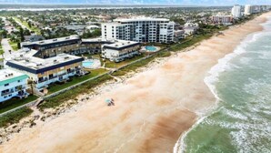 A beachfront hotel with multiple buildings, a pool, and a beach. - Direct Oceanfront 1/1 king first floor, oceanfront Patio, pool beach steps away. (Ormond Beach)