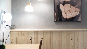 A dining area with a wooden table and chairs, two pendant lights, and a wall-mounted painting of flowers. - Jinyou Hotel (Chishang)