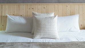 A bedroom with a wooden headboard, white bedding, and decorative pillows. - Jinyou Hotel (Chishang)
