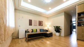 A modern living room with a sofa, a coffee table, a lamp, and a potted plant. - Jinyou Hotel (Chishang)