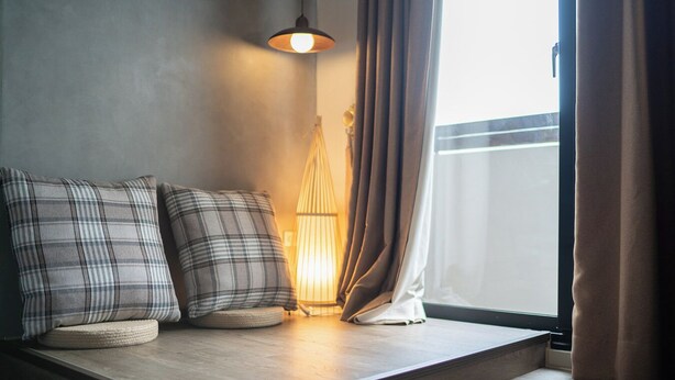 A cozy seating area with a cushioned bench, a lamp, and curtains. - Jinyou Hotel (Chishang)