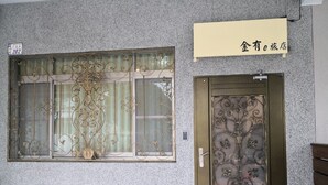 A building facade with a window featuring ornate metalwork and a door with similar design. - Jinyou Hotel (Chishang)