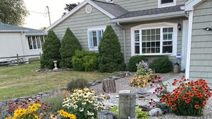 A residential house with a well-maintained garden featuring various flowers and a gravel pathway.
