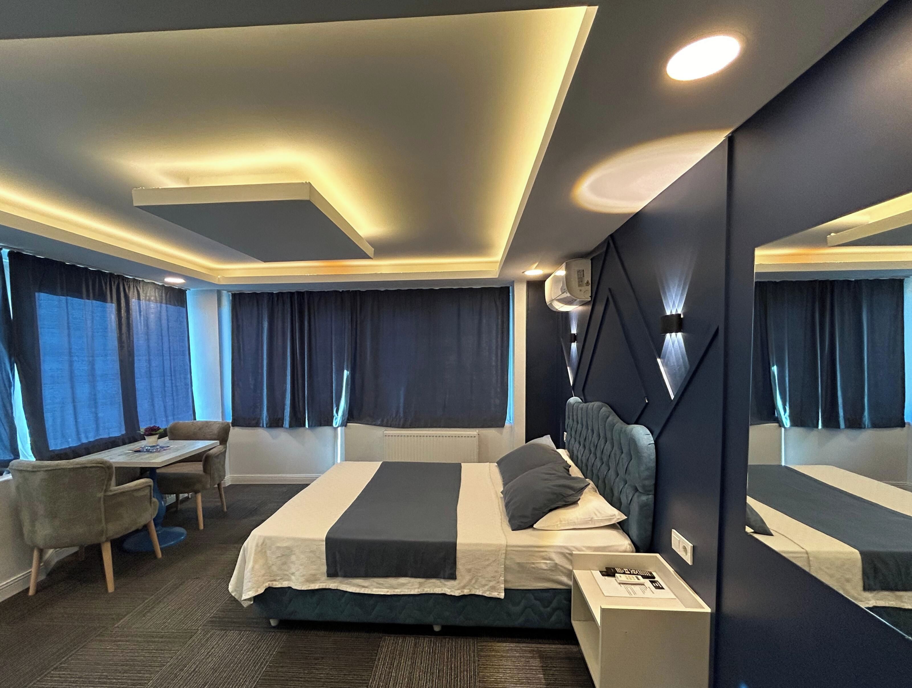 A modern hotel room with a large bed, bedside tables, a desk, and a chair.