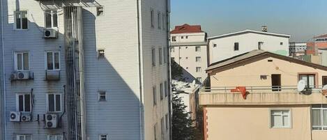 Un edificio de varios pisos con fachada curva, unidades de aire acondicionado y una lona azul en la parte baja.