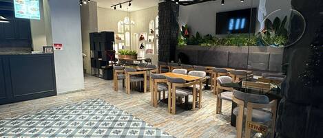 A modern interior with wooden flooring, a patterned rug, and a seating area with tables and chairs.
