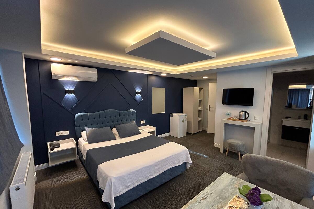 Moderni hotellihuone, jossa on suuri sänky, yöpöydät, työpöytä, tuoli ja televisio.