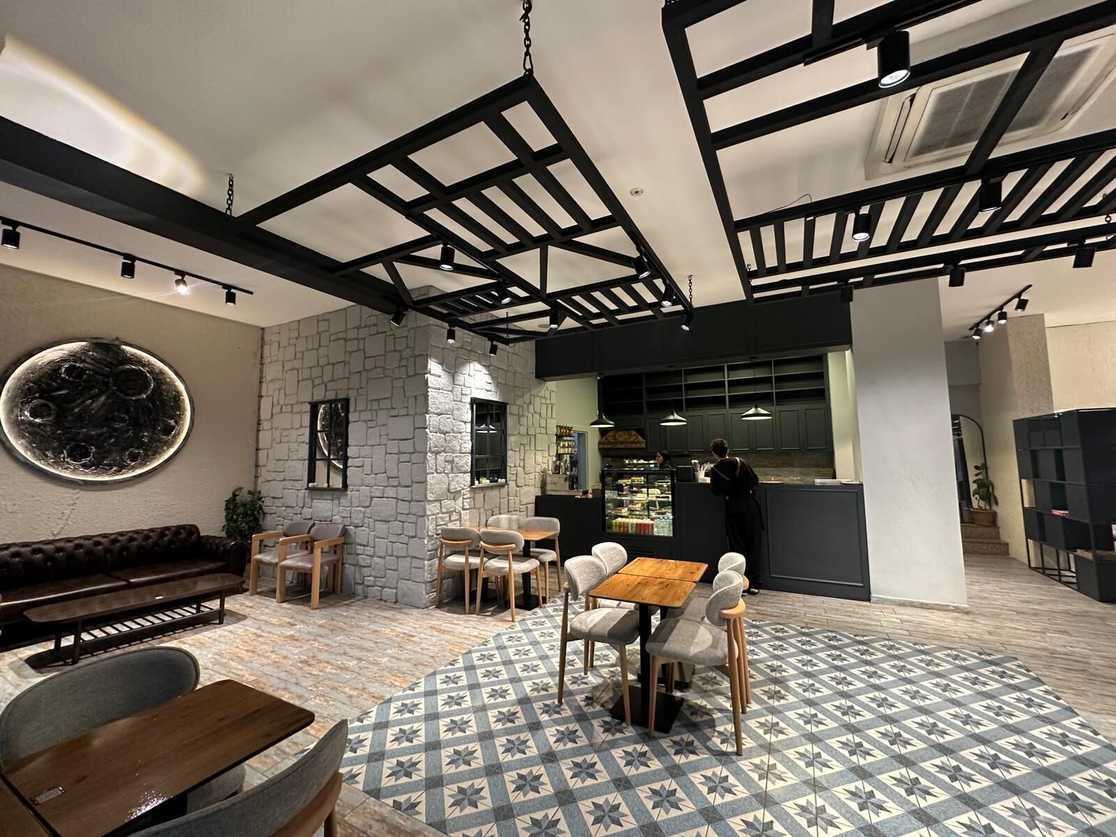 Un café con paredes de piedra, muebles de madera y un piso con diseño.