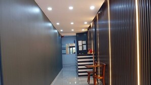 A hallway with a reception desk, wooden chairs, and a modern design with vertical light strips. - Kavacık Asia Hotel (Beykoz)