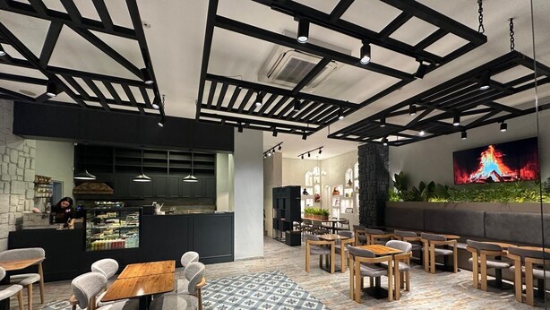 A modern restaurant interior with a bar area, seating arrangements, and a television screen displaying a fire. - Kavacık Asia Hotel (Beykoz)