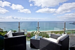 A balcony with wicker furniture overlooking a beach.
