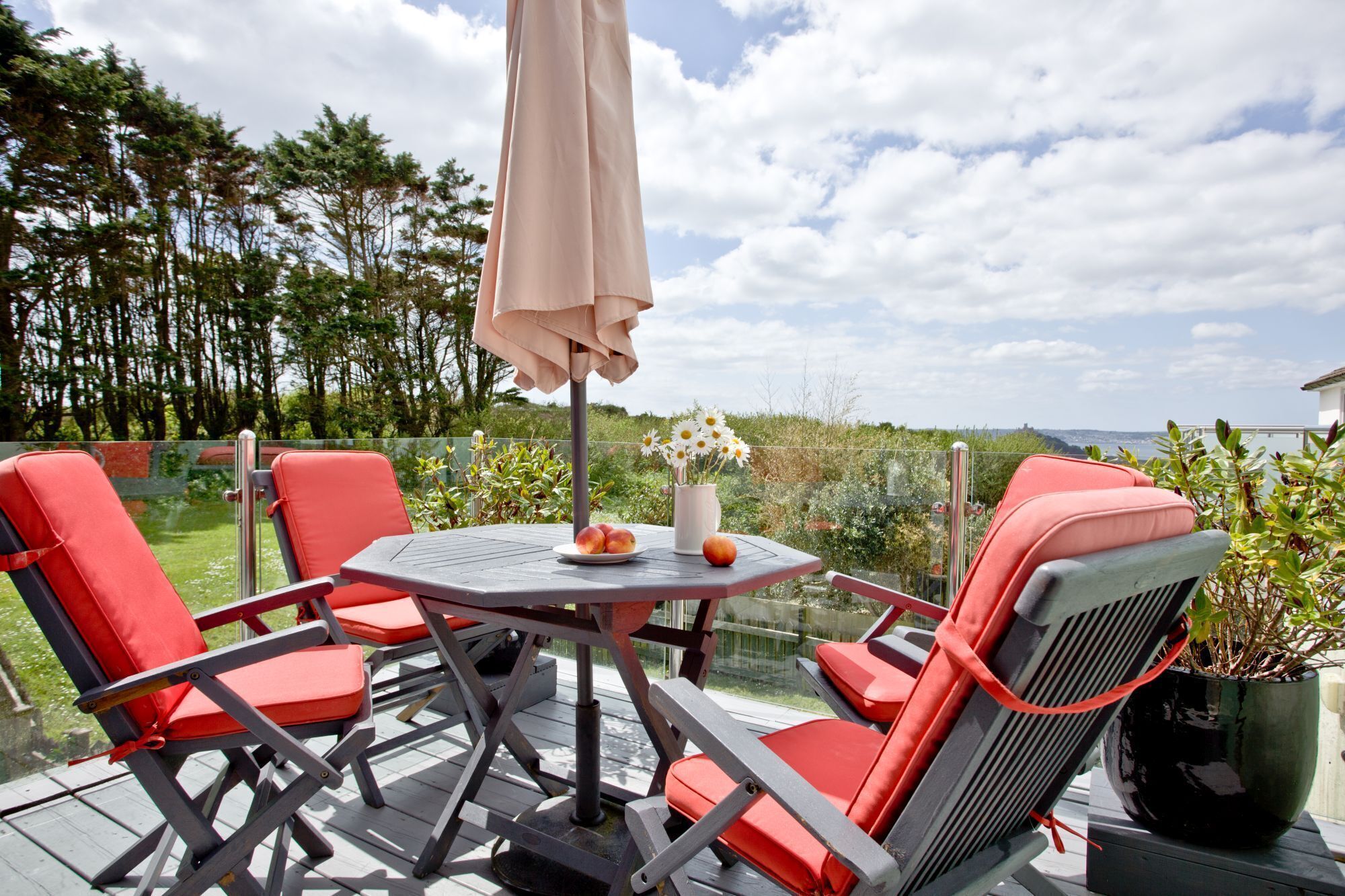 A patio with a table, chairs, and a potted plant.