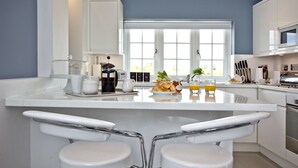 Una cucina moderna con isola centrale, sgabelli da bar bianchi e un'ampia finestra che offre luce naturale.
