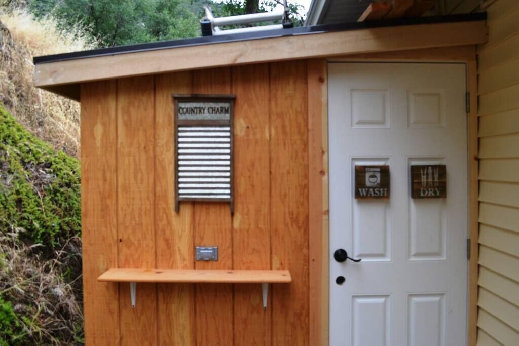 Une structure en bois sur laquelle on peut lire l’inscription « Charme rustique », et une porte avec les indications « LAVAGE » et « SÉCHAGE ».