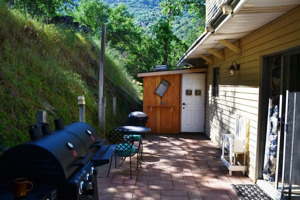 A patio with a barbecue grill, a table, and chairs.
