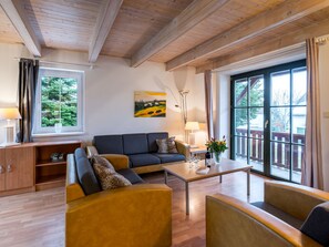 Un salon moderne avec un canapé, des fauteuils, une table basse et un tableau accroché au mur.