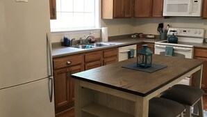A kitchen with wooden cabinets, a refrigerator, a microwave, a stove, and a sink. - Wakulla River Retreat- Manatee Cottage  (Crawfordville)