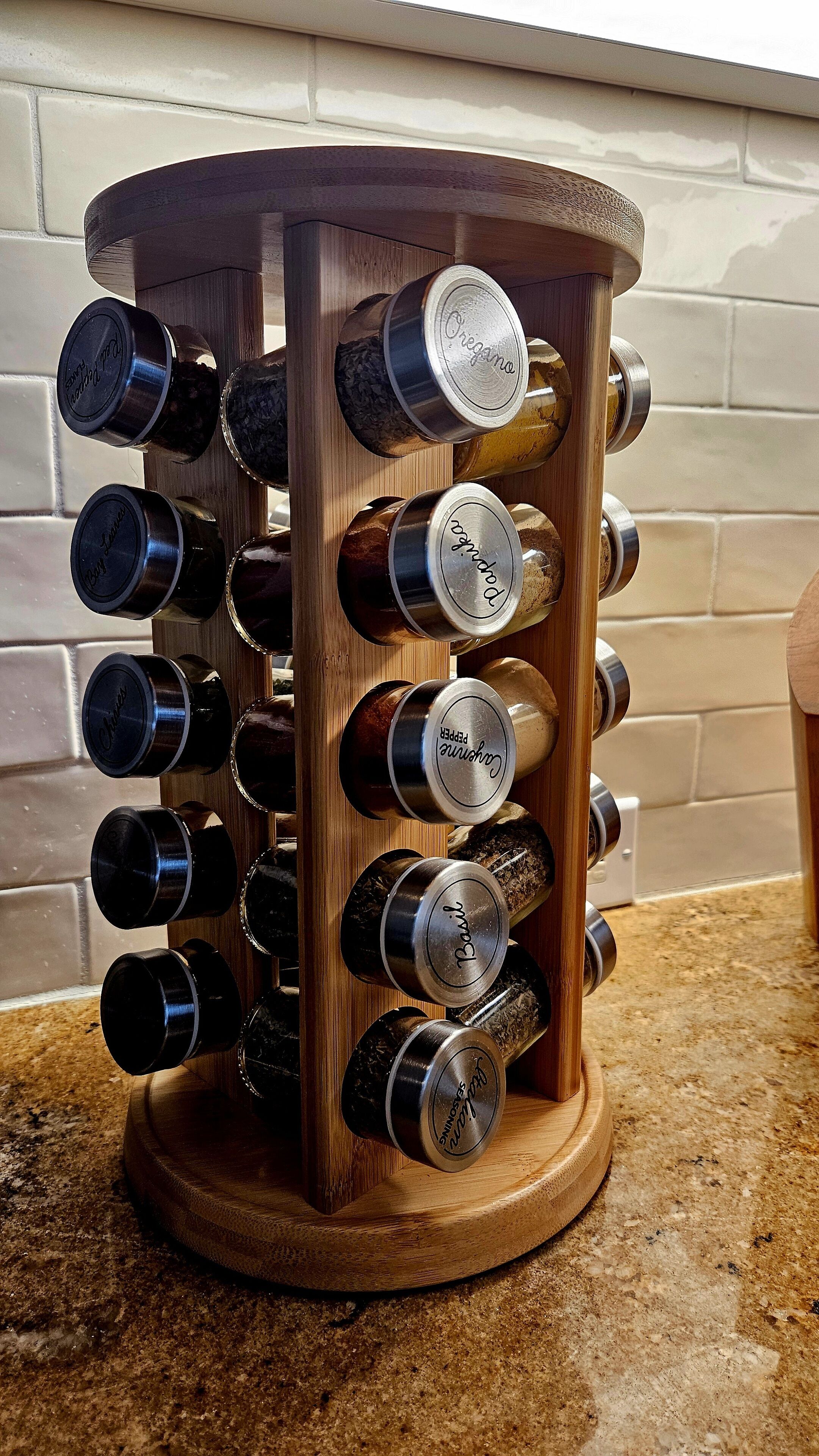 Un étagère à épices en bois, dotée de plusieurs pots contenant différentes épices, chacun étant étiqueté avec des noms tels que « Origan », « Basilic » et « Piment ».