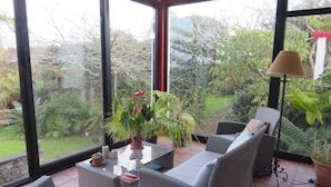 Une véranda meublée de meubles en osier, une table décorée de bougies et des plantes en pot.