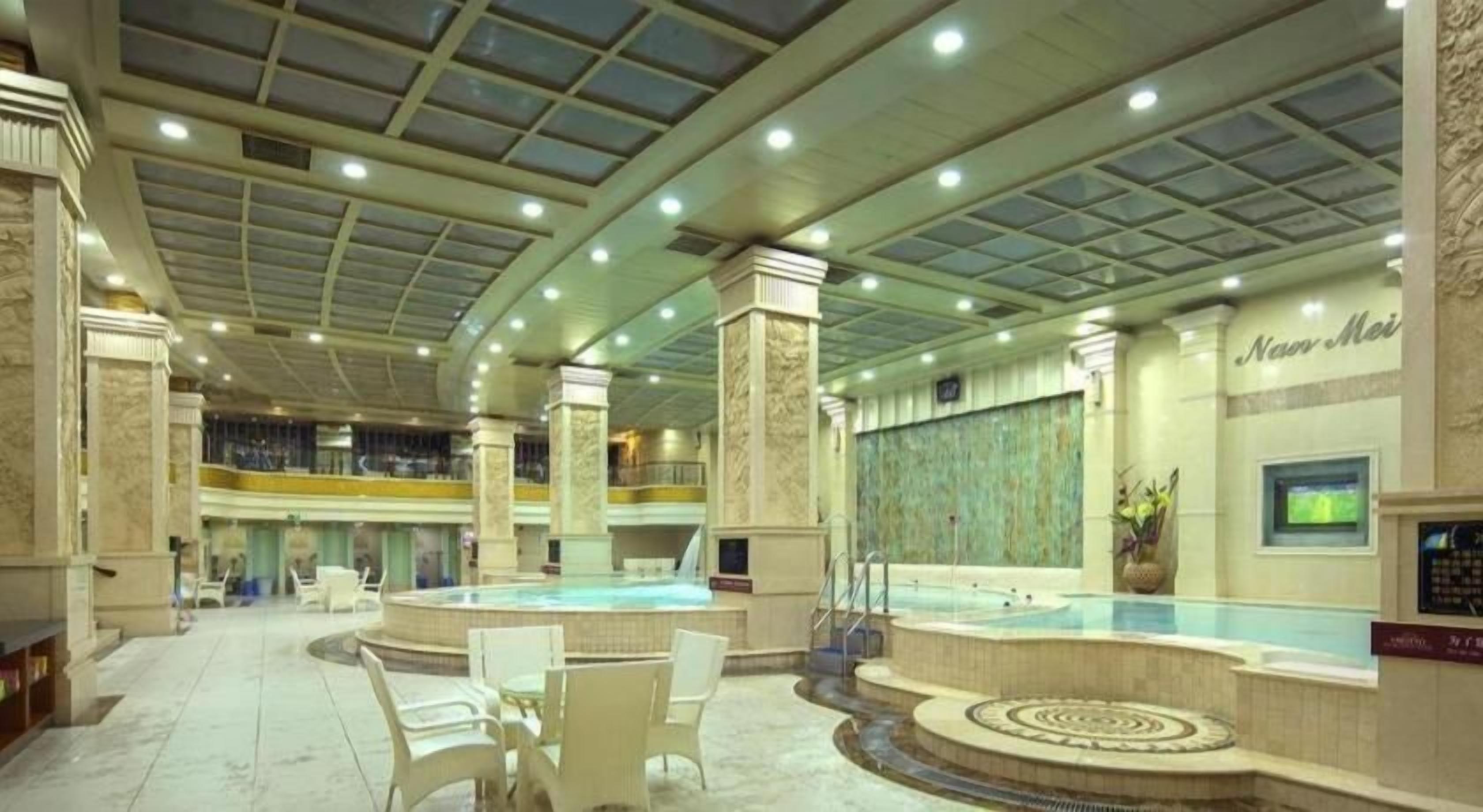 A spacious indoor swimming pool area with multiple seating areas and a large central pool.
