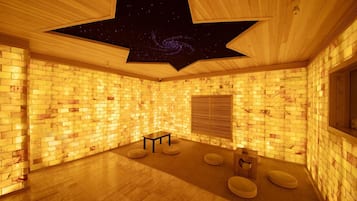 Une pièce avec un mur en briques, un plafond en bois orné de motifs en forme d’étoiles, une petite table et des sièges rembourrés.