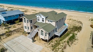A beachfront house with a large deck, multiple stories, and a staircase leading to the entrance. - Quiet Time | Oceanfront (Virginia Beach)