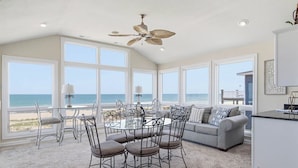 A spacious room with a large dining table, a sofa, and a ceiling fan. - Quiet Time | Oceanfront (Virginia Beach)