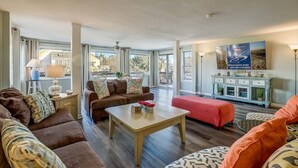 Ein großzügiges Wohnzimmer mit einem großen Fenster, einer Sofagarnitur, einem Couchtisch und einer Kommode mit Dekoration.