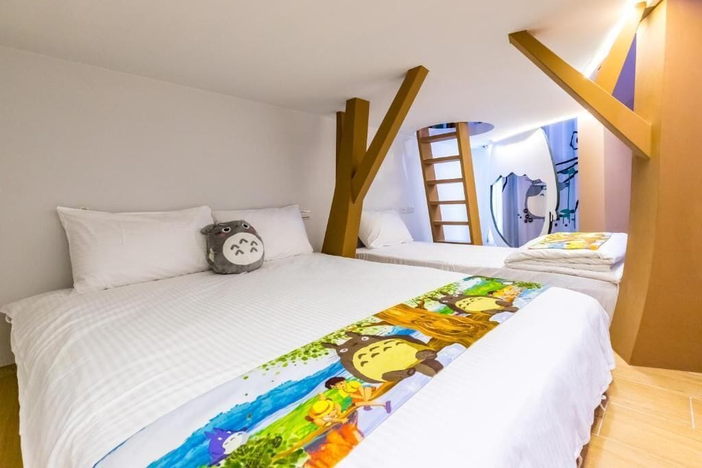 A hotel room with a large bed, a smaller bed, a ladder, and a bathroom visible through an open door.