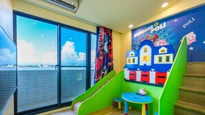 A children's play area with a slide, a small table, and a colorful mural. - Songfeng Qinzi Homestay (Wujie)