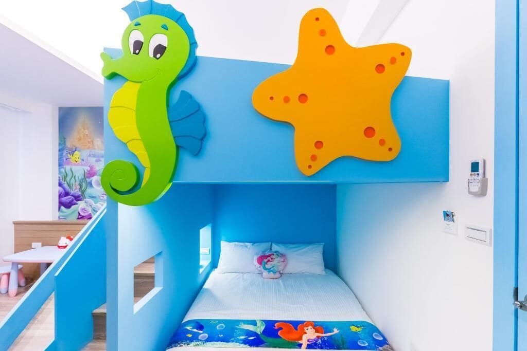 Habitación apta para niños con litera, decoración de caballito de mar verde y un cuadro de estrella de mar.