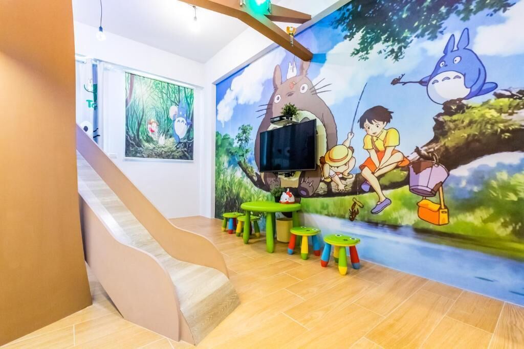 A children's play area with a slide, a mural of animated characters, and small tables.