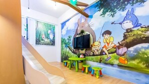 A children's play area with a slide, a mural of animated characters, and small tables. - Songfeng Qinzi Homestay (Wujie)