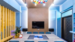 A modern conference room with a large table, blue chairs, a flat-screen TV, and a wooden slat wall. - Songfeng Qinzi Homestay (Wujie)