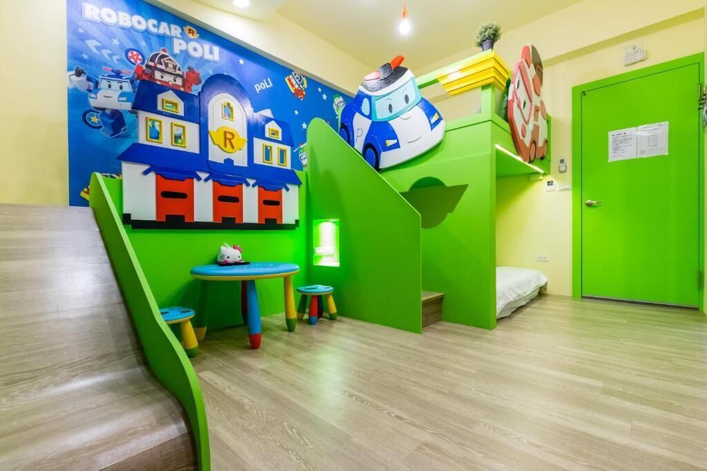 Een kinderspeelruimte met een kleurrijke muurschildering, een kleine tafel en een groene speelhuisje.