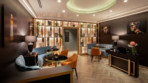 Un moderno vestíbulo de hotel con mostrador de recepción, zona de estar y plantas decorativas.