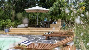 Ein Poolbereich mit Liegestühlen, einem Tisch und einem Sonnenschirm.