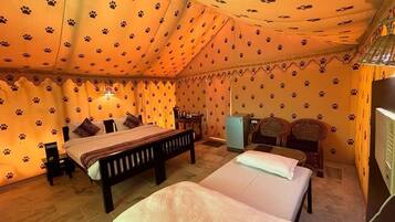 Une chambre avec deux lits, une petite table, une chaise, un téléviseur et un mur orné d’un motif représentant des empreintes de pattes.