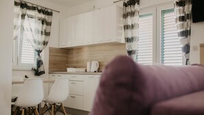 Una cocina moderna con armarios blancos, encimera de madera y dos sillas blancas.