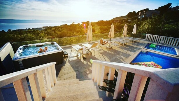 Terraza en la azotea con jacuzzis, sillones de descanso y una piscina.