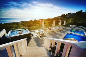 Terraço no telhado com hidromassagens, espreguiçadeiras e piscina.