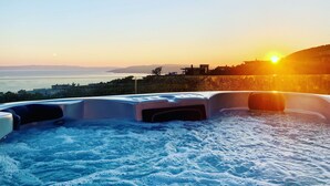 Un jacuzzi con vista al atardecer sobre el mar.